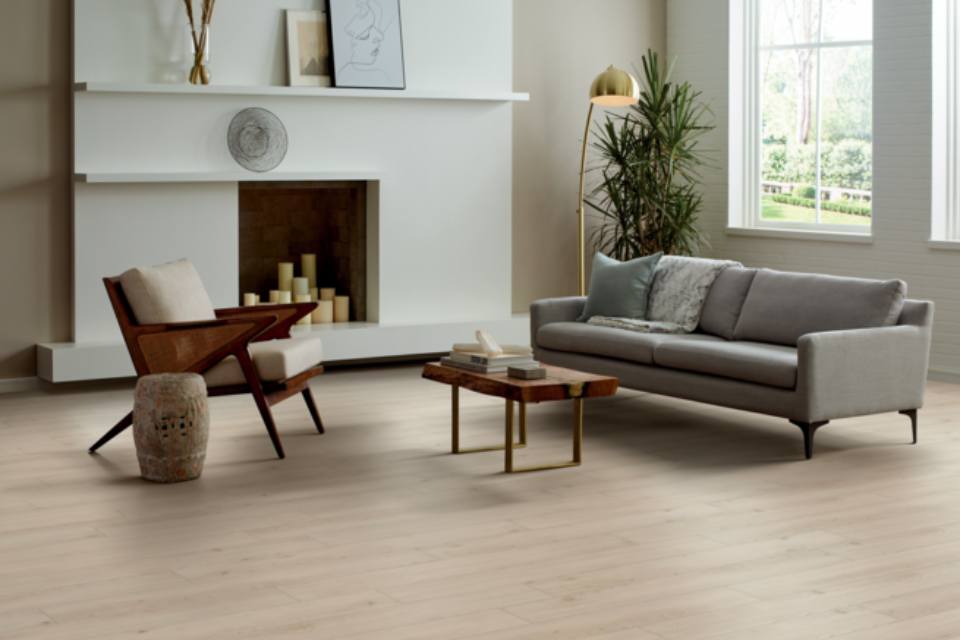 light wood look flooring in living room with gray couch and wood accent furniture.